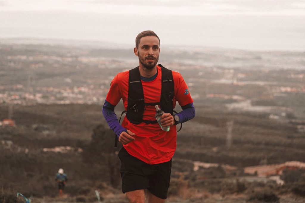 Coureur de trail équipé d’un gilet d’hydratation et d’une flasque