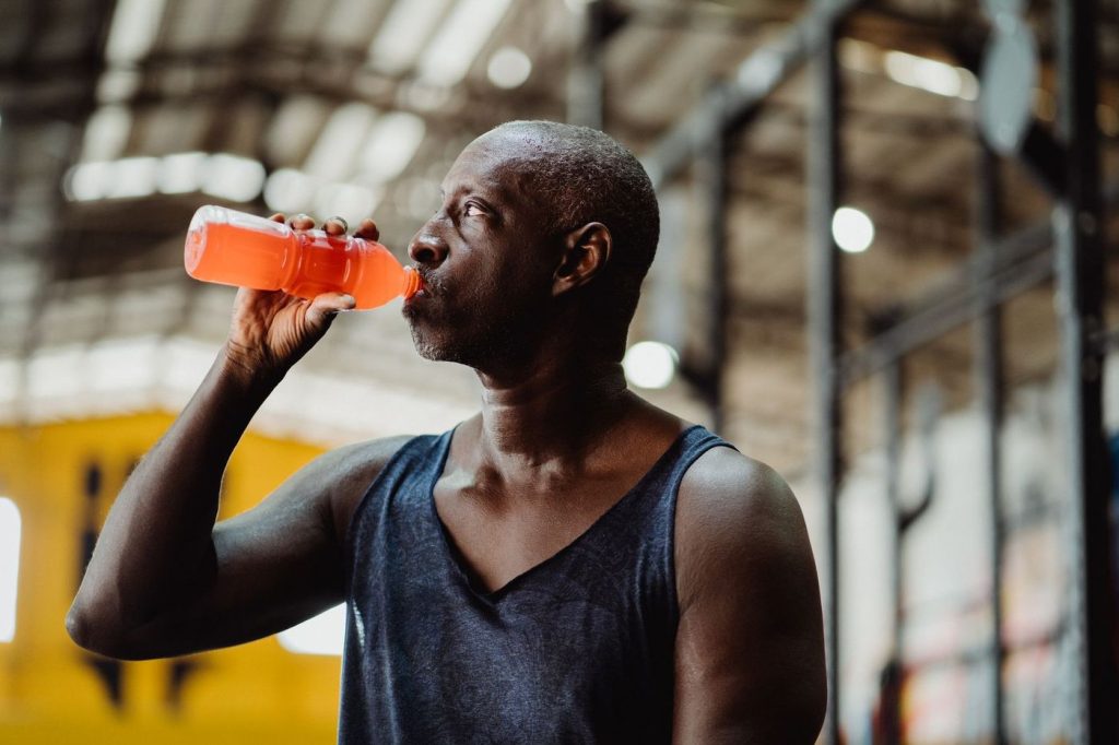 Homme qui boit une boisson pour sportifs orange