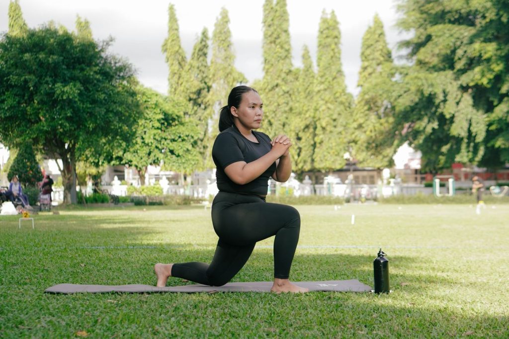 Femme en fente avant sur un tapis, dans un parc