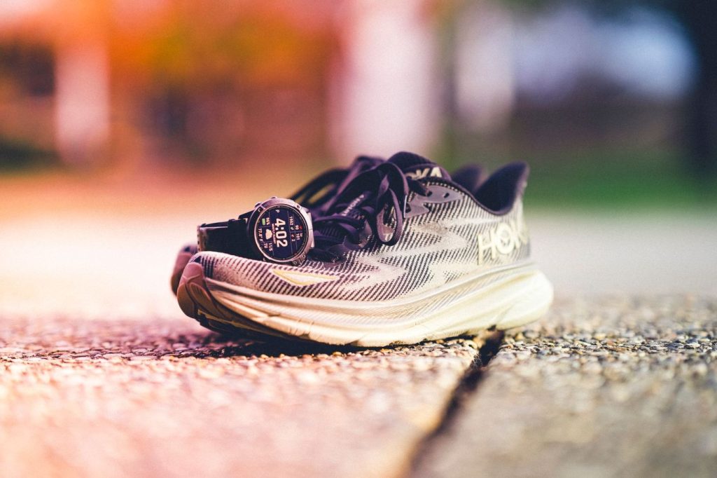 Chaussures de course Hoka et montre GPS posées sur le trottoir