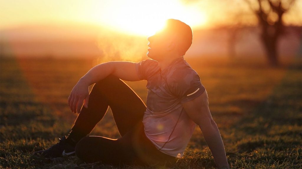 Coureur assis au coucher du soleil qui reprend son souffle