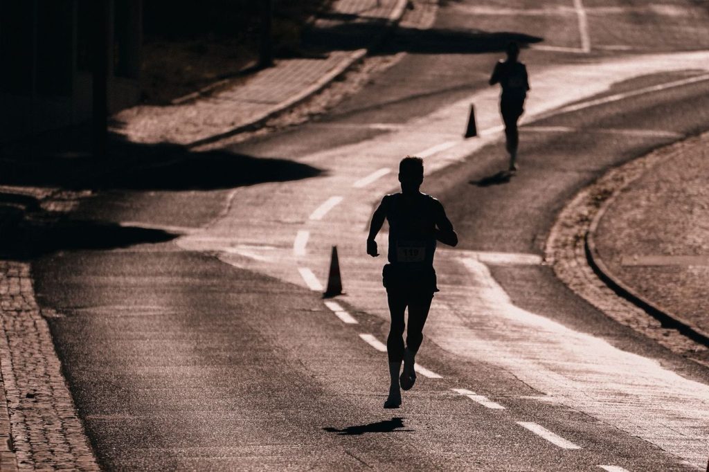 Silhouette d’un coureur sur une route entre des plots